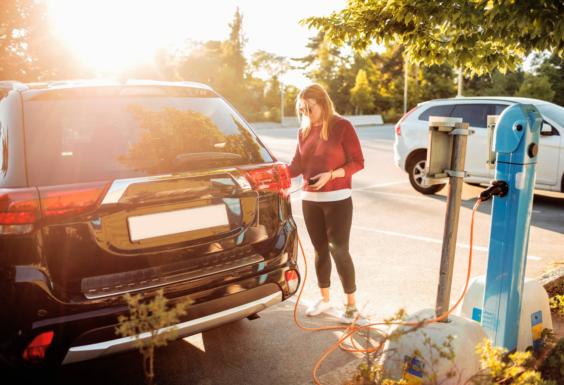 Tyttö lataamassa sähköautoa.