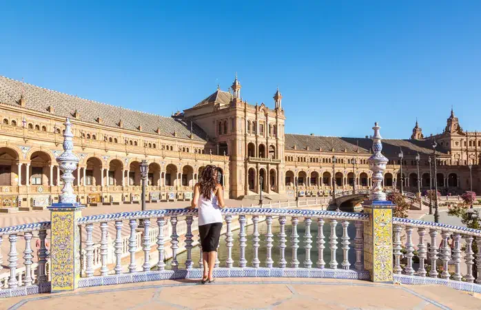 Tourist on bridge in Plaza de Espana, looking at south wing of central building, Seville